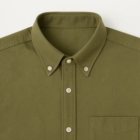 Camisa masculina Oxford verde militar manga longa, com gola colarinho, bolso no peito e botões frontais brancos, estilo casual e elegante.
