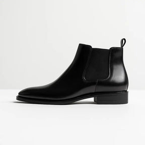 bota chelsea masculina de couro polido preto com elástico lateral e bico fino – estilo elegante sobre superfície de madeira