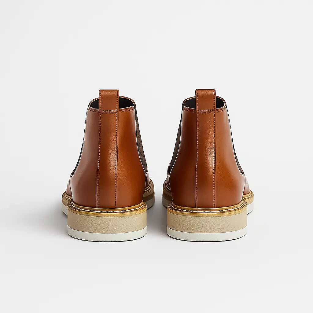 Bota Chelsea em couro legítimo com elástico lateral e solado branco.