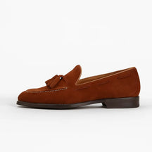 Loafer masculino em camurça marrom com tassel e costura branca aparente, estilo clássico europeu artesanal.