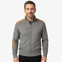 Homem vestindo suéter cinza masculino com zíper e detalhes em camurça caramelo nos ombros e cotovelos, estilo casual sofisticado para o inverno.