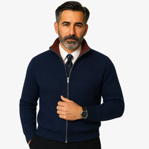 Homem elegante vestindo suéter social azul marinho com zíper e camisa branca com gravata, estilo sofisticado para ocasiões formais.