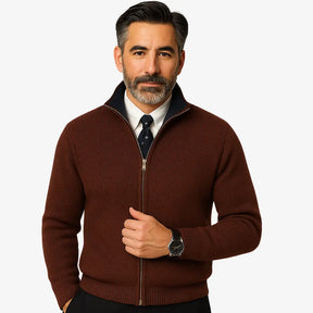 Homem elegante vestindo suéter social marrom com zíper e camisa branca com gravata, estilo sofisticado para ocasiões formais.