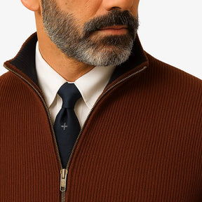 Homem elegante vestindo suéter social marrom com zíper e camisa branca com gravata, estilo sofisticado para ocasiões formais.