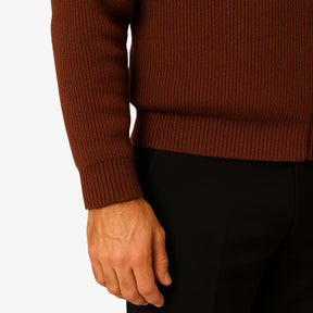 Homem elegante vestindo suéter social marrom com zíper e camisa branca com gravata, estilo sofisticado para ocasiões formais.