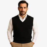 Homem usando colete masculino tricot slim cinza com gola V sobre camisa preta. Peça leve e elegante para dias de frio moderado.