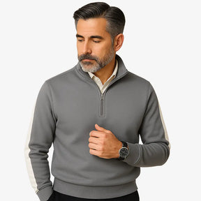 Homem maduro vestindo suéter cinza masculino com zíper e detalhes brancos nas mangas, estilo casual e sofisticado.